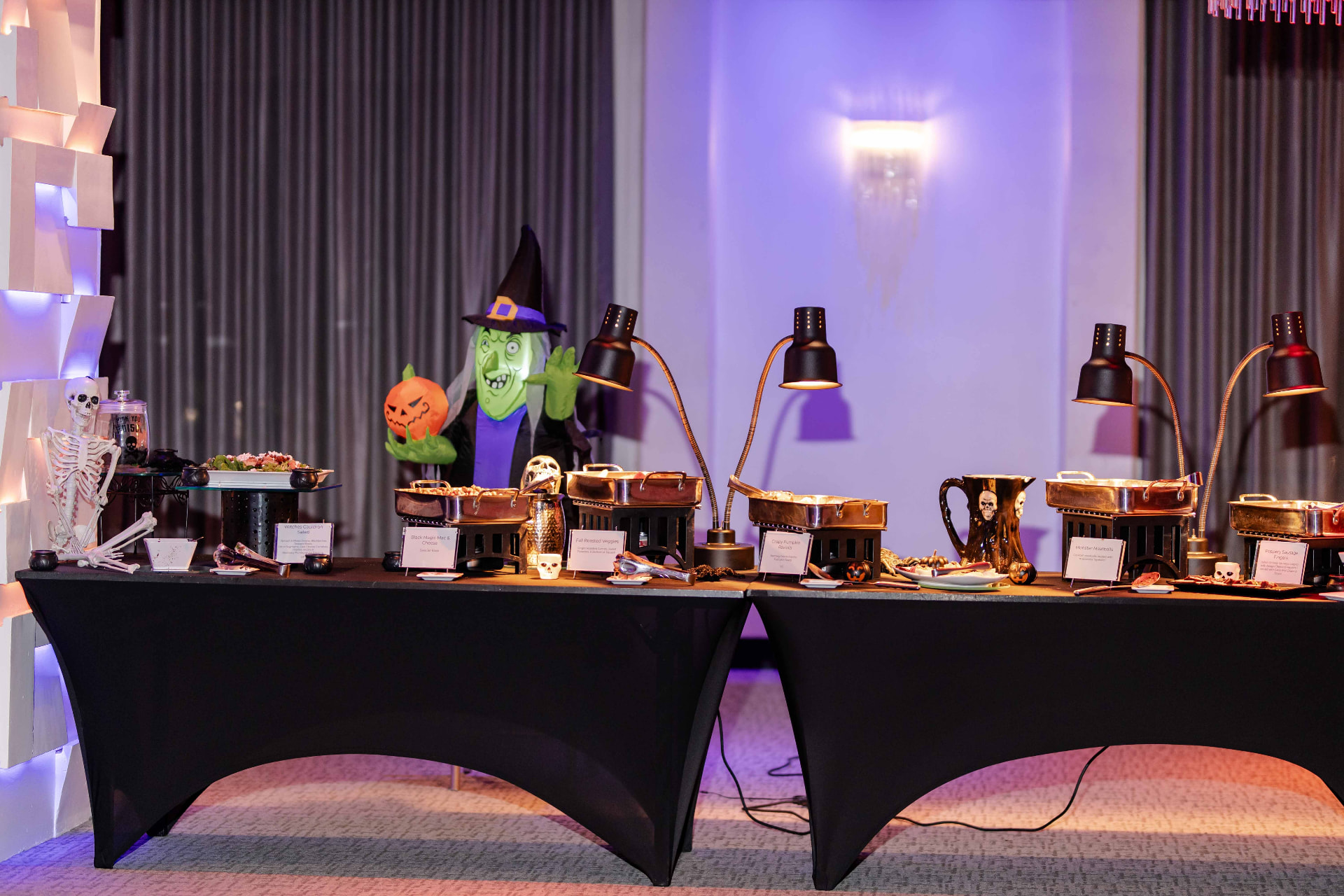 Halloween-themed buffet displayed under warming lamps at The MEZZ