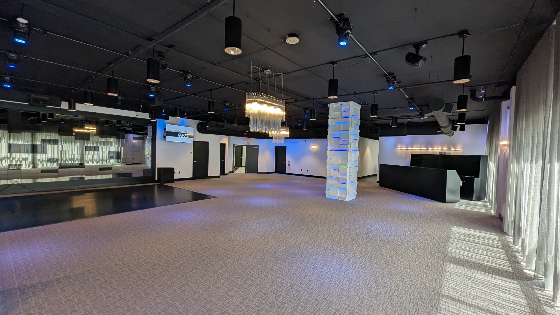 Wide view of the open floor plan, wood dance floor and built-in bar in the main event space at The MEZZ